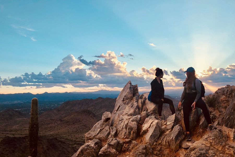 Two hikers resting on a desert summit at sunset