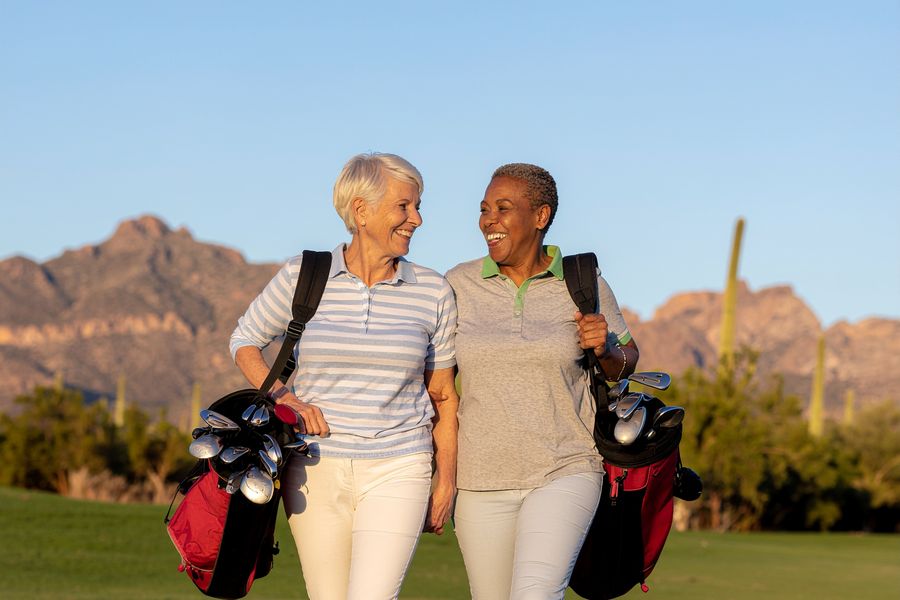 Two friends laughing as they walk a desert golf course